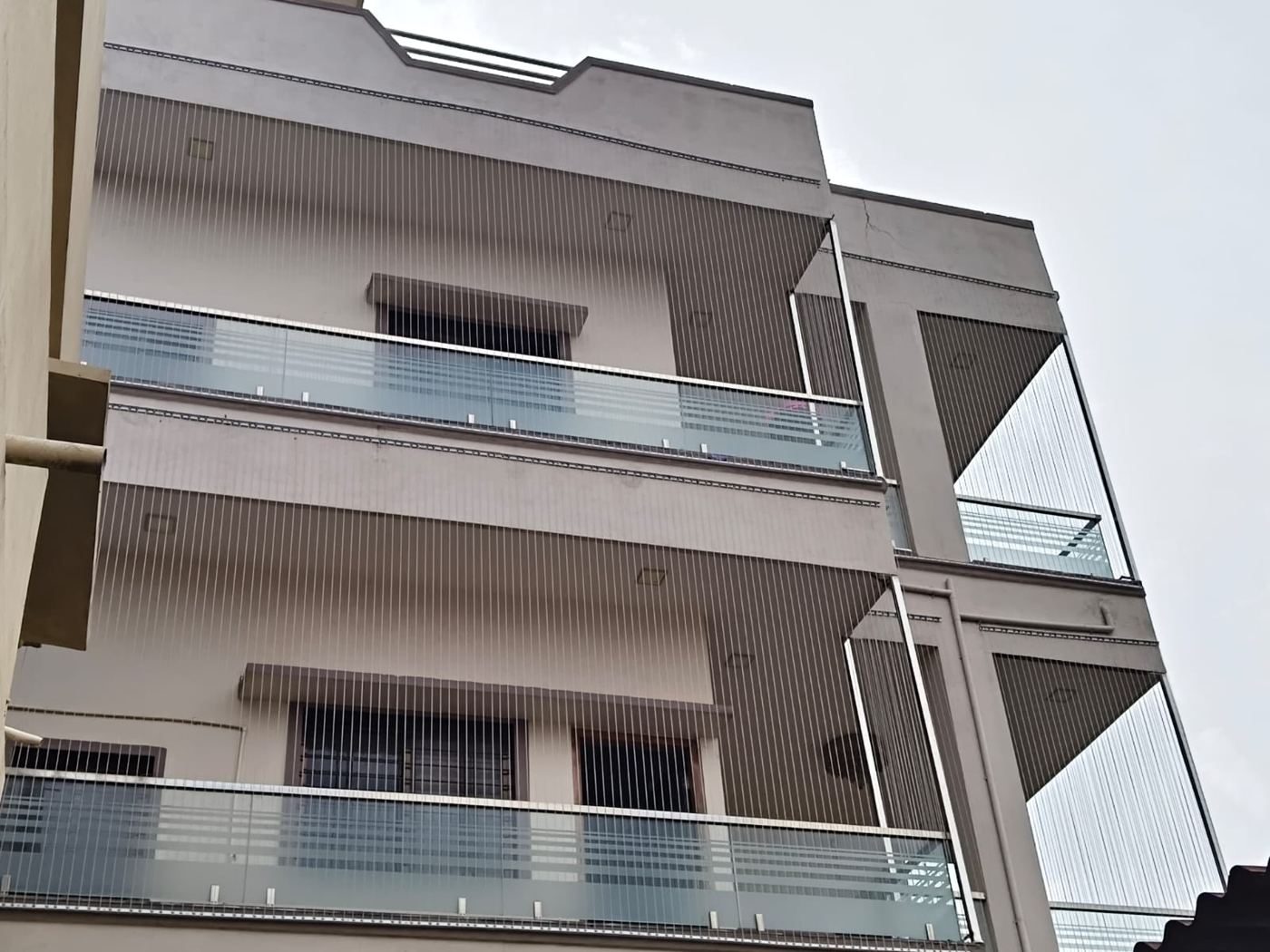 Invisible grill cables installed across every balcony of a three-storey home by Tirupati Bird Netting