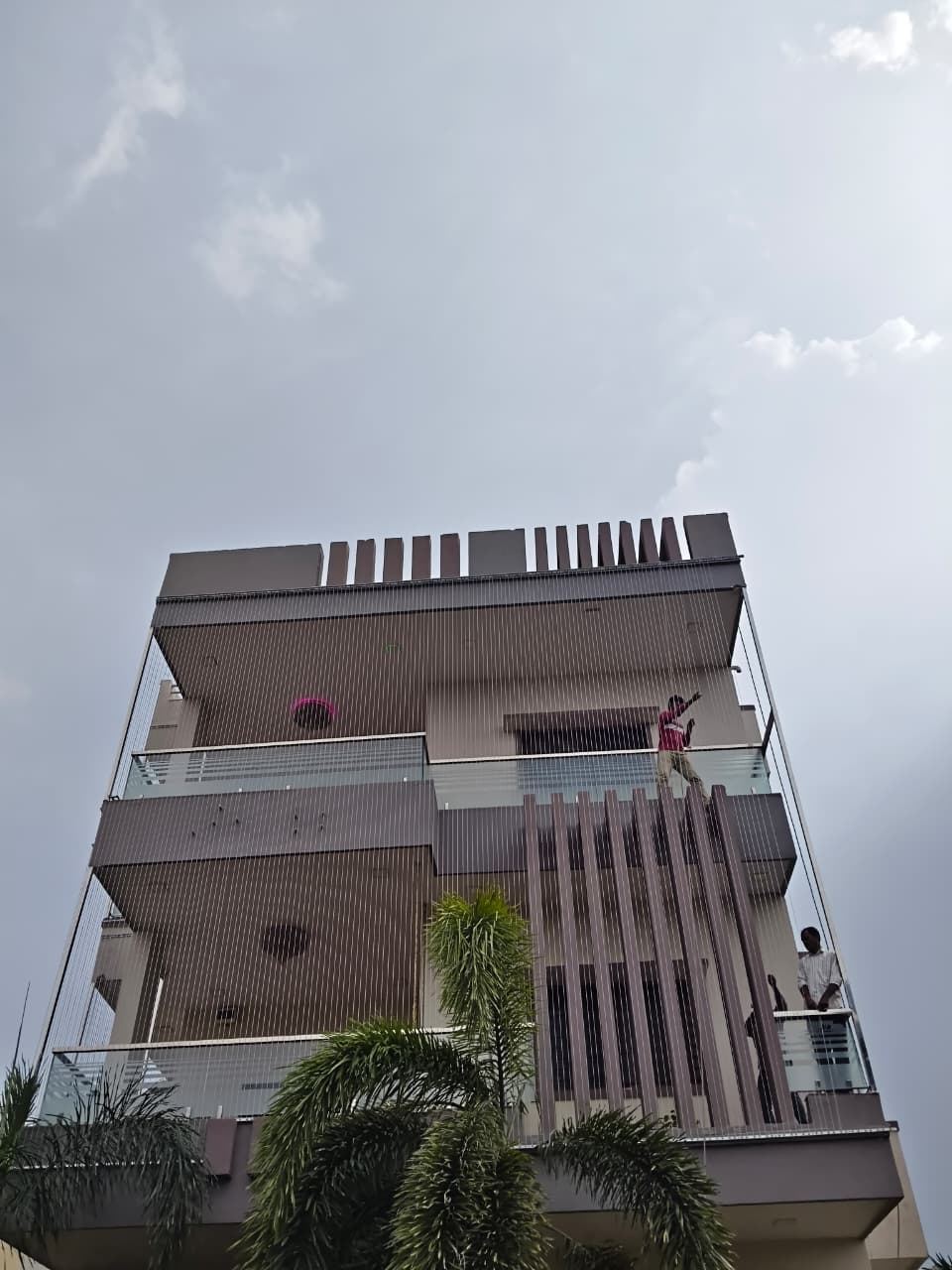 Installers working on the facade of a three-storey house fitting invisible grills