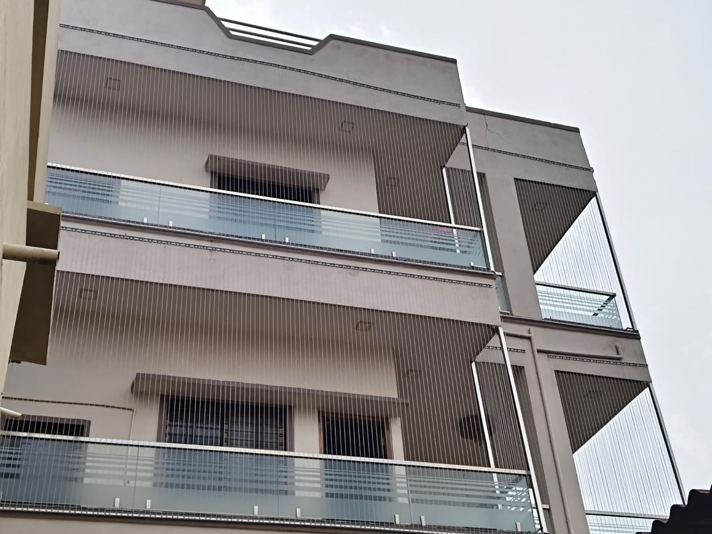 Front view of a three-storey house with invisible grills on all balconies